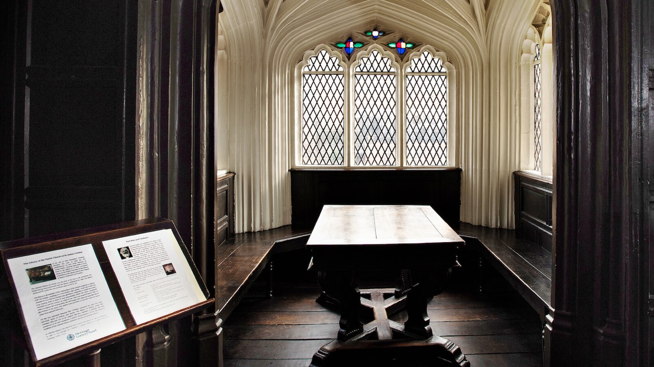 Ein alter Tisch in einem Erker umrundet von Fenstern.