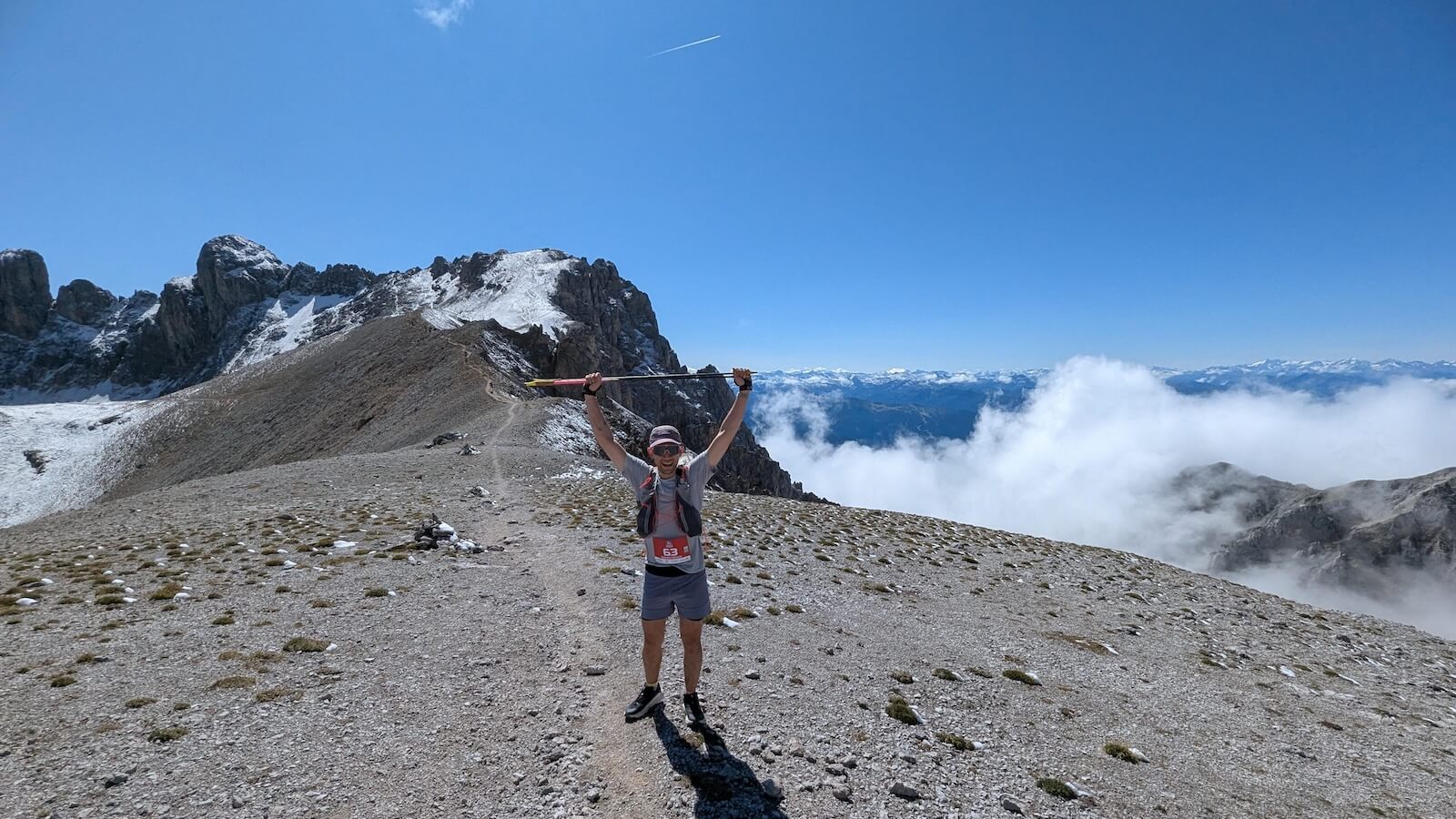 Ein Mann auf einem Berg streckt die Arme jubelnd nach oben.
