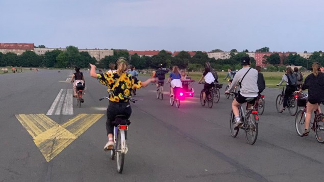 Eine Traube aus Menschen auf dem Fahrrade auf dem Tempelhofer Feld. Eine Person hat die Arme weit ausgebreitet